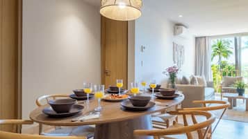Un espace repas comprenant une table ronde en bois, plusieurs chaises et un luminaire central.