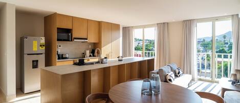 Een moderne keuken met een centraal eiland, een eettafel met stoelen en een stadsgezicht door grote ramen.