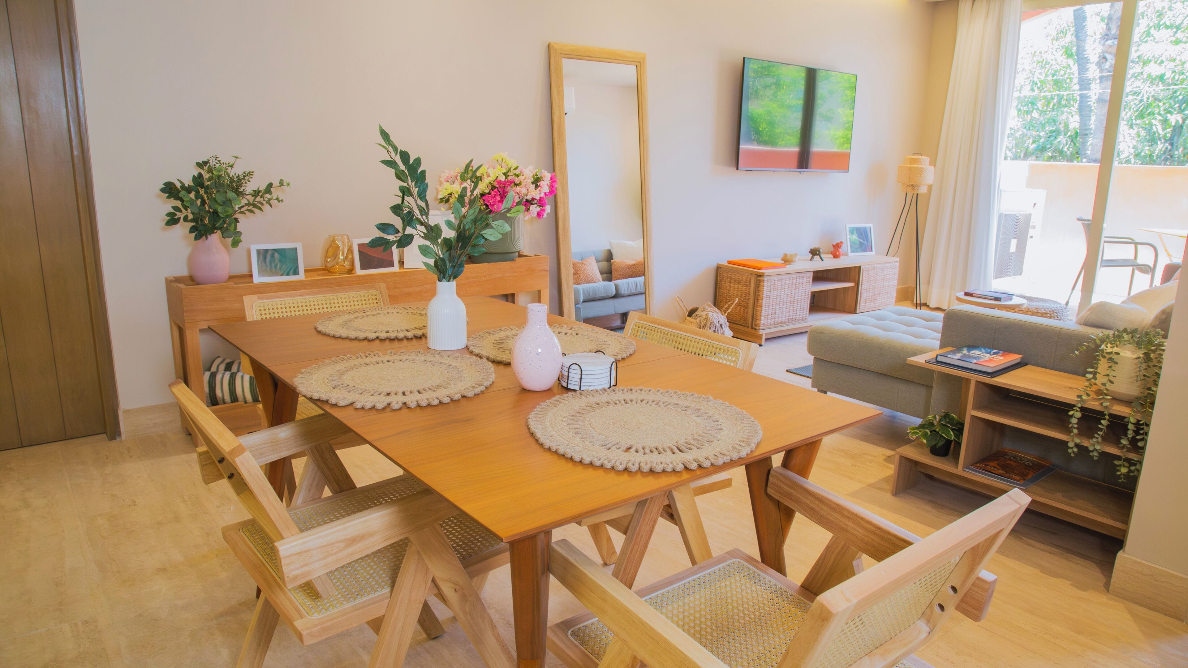 A dining area with a wooden table, woven chairs, and a mirror on the wall.