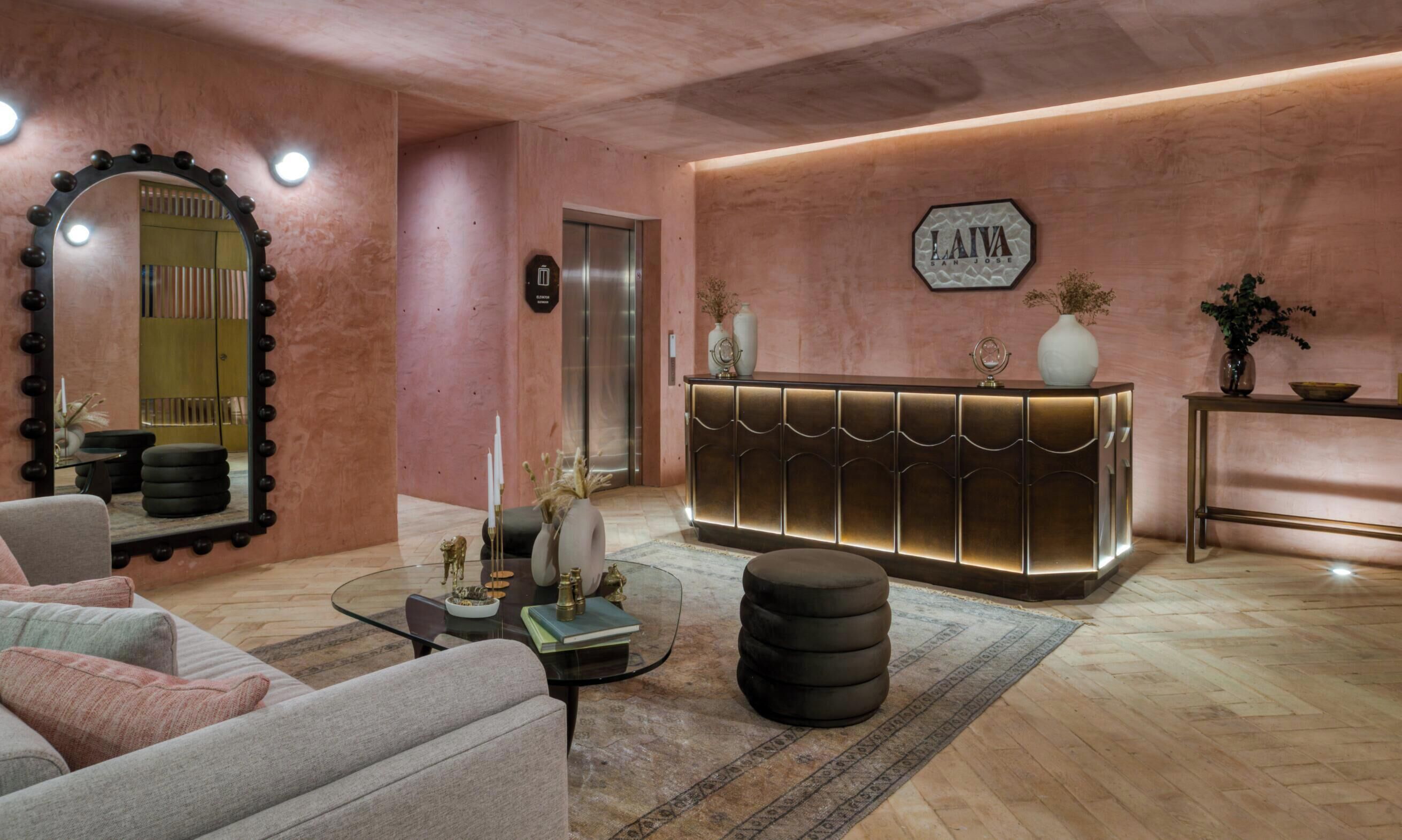 A modern lobby with a reception desk, a large mirror, a sofa, and a coffee table.