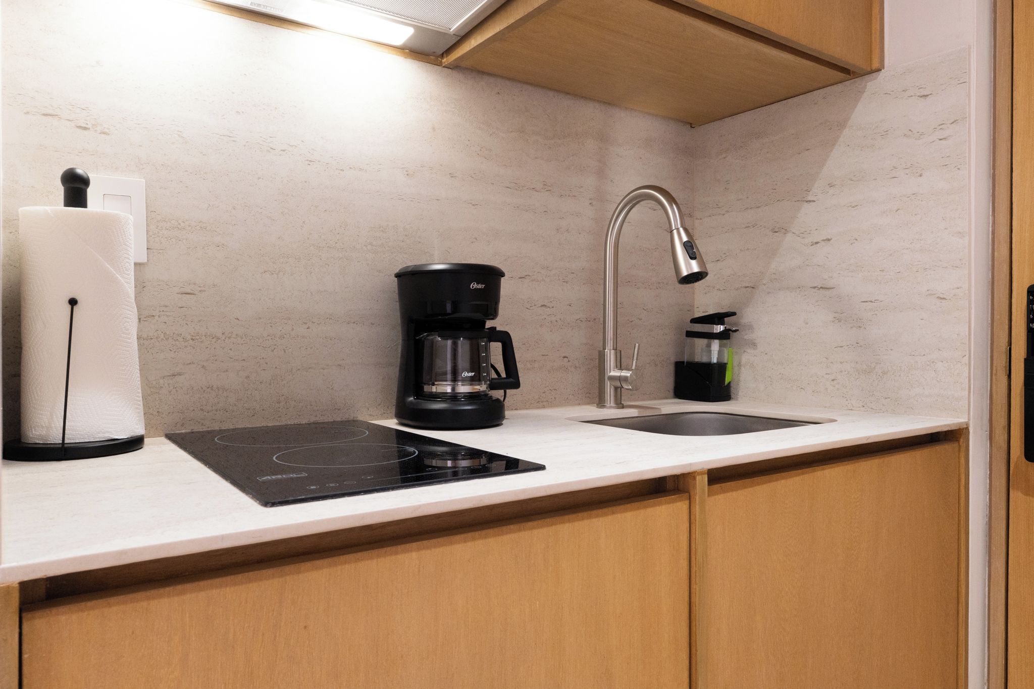 A modern kitchen with a built-in induction cooktop, a coffee maker, and a sink with a faucet.