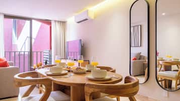 A modern dining area with a round wooden table, white plates, and glasses of orange juice.