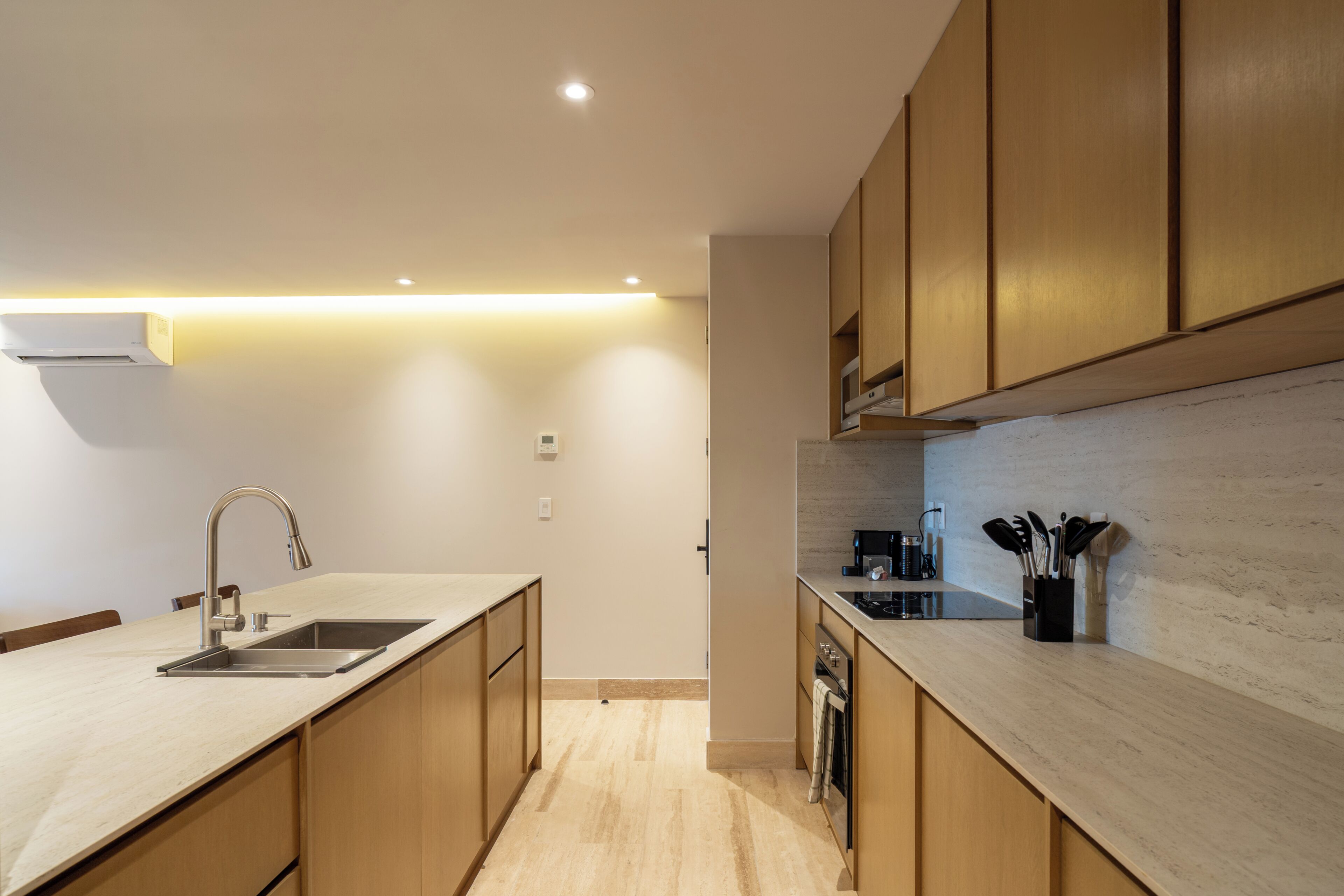 Una cocina moderna con armarios de madera, un lavamanos de acero inoxidable y un horno empotrado.