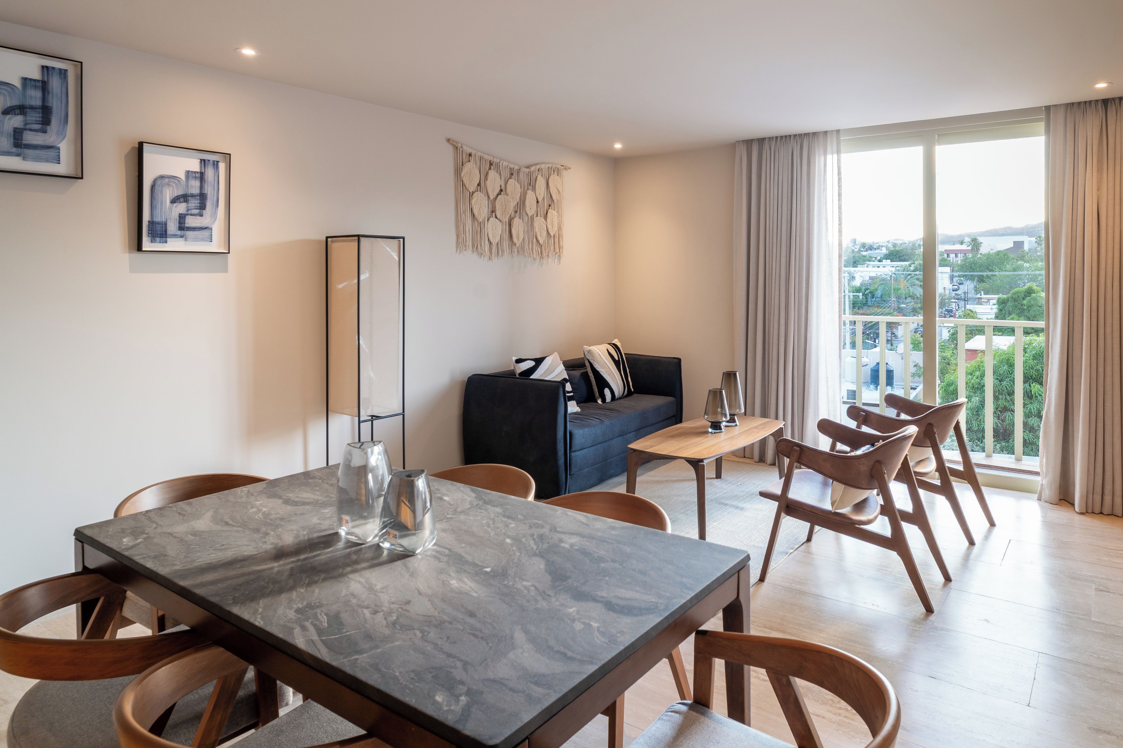 A modern living room with a dining area, a sofa, and a large window with a view.