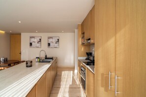 A modern kitchen with wooden cabinets, a marble countertop, and stainless steel appliances.