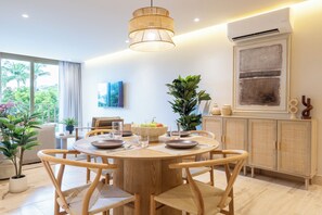 A modern dining area with a round wooden table, chairs, and a hanging light fixture.