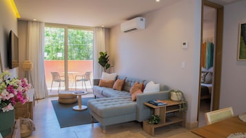 A modern living room with a sofa, a small table, and a dining area with chairs.