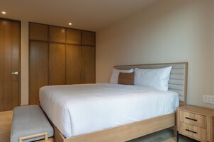 A bedroom with a bed, a bench, a nightstand, and wooden wardrobes.