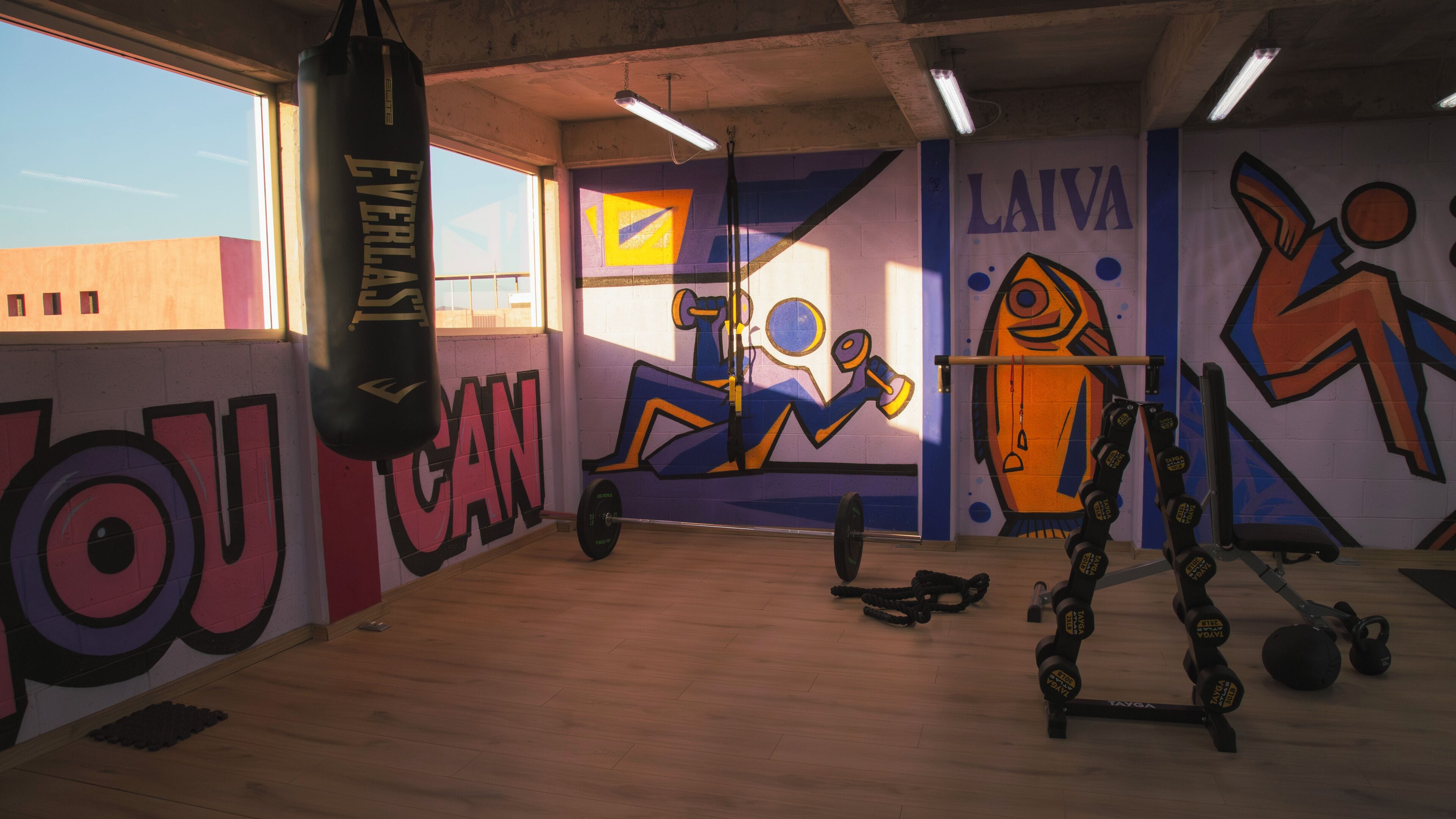 A gym with a punching bag, exercise equipment, and motivational wall art.