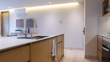 A modern kitchen with a central island, stainless steel appliances, and recessed lighting.