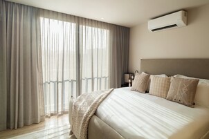 Un dormitorio moderno con una cama grande, cabecera y equipo de aire acondicionado.