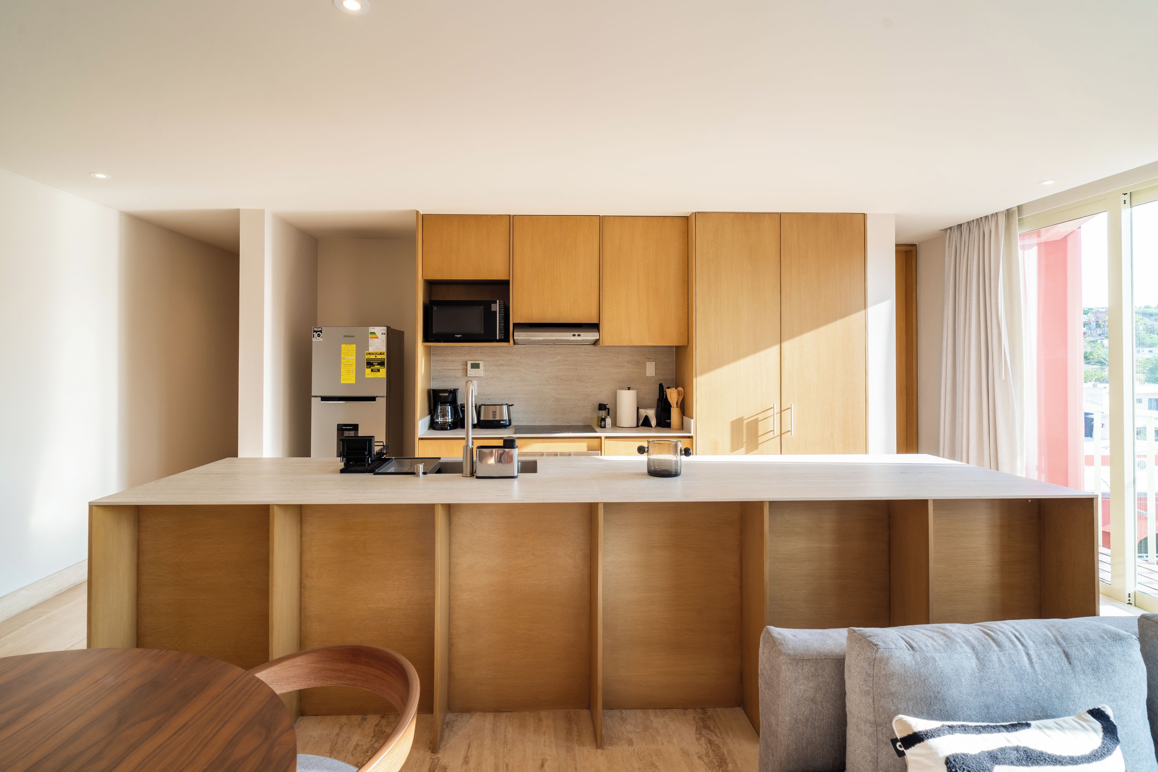 A modern kitchen with wooden cabinetry, a built-in microwave, and a stainless steel sink.