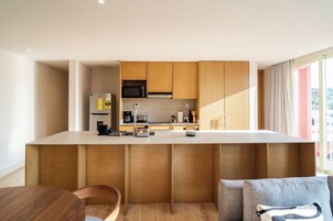 Una cocina moderna con armarios de madera, microondas integrado y pileta de acero inoxidable.