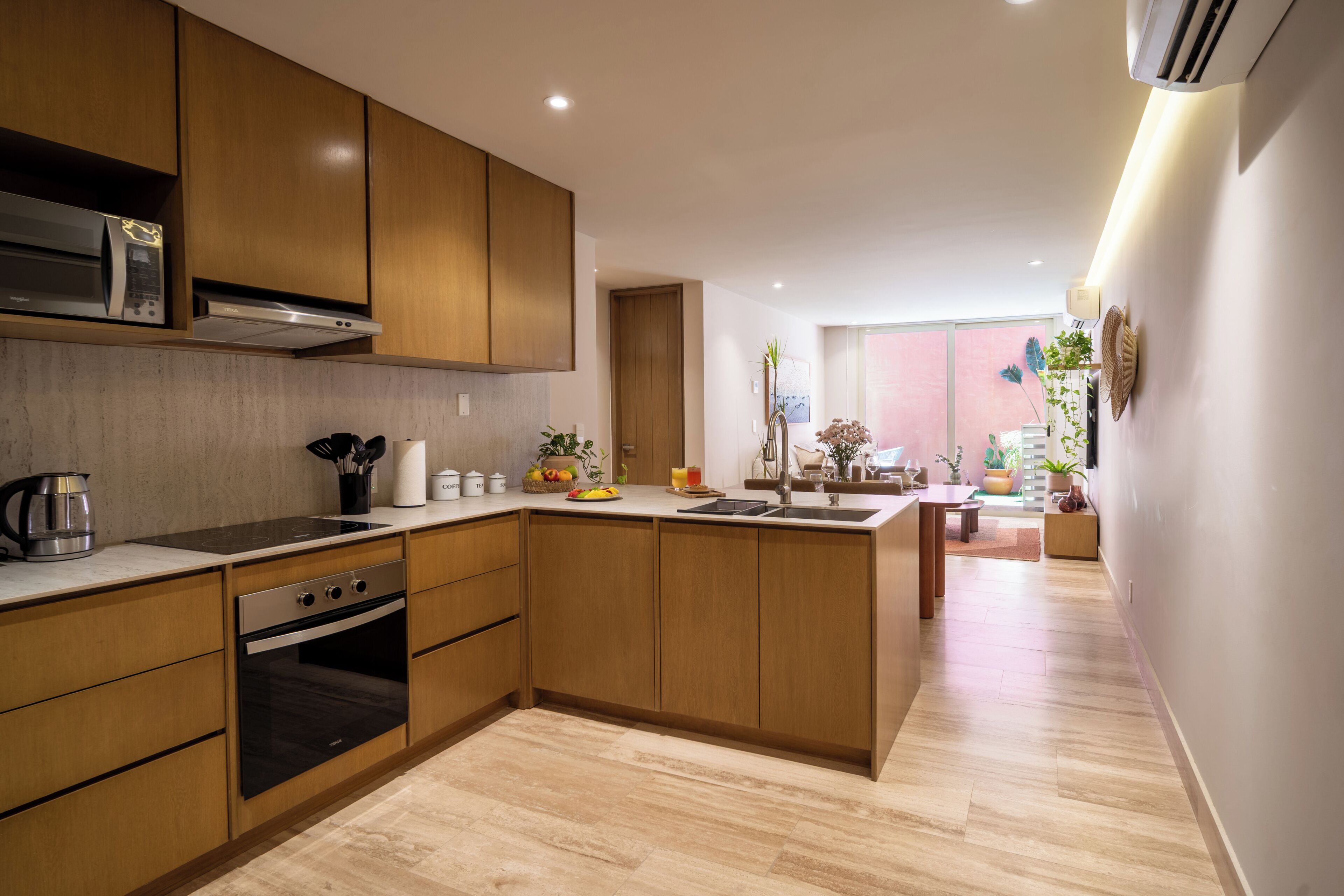 Una cocina moderna con armarios de madera, horno empotrado e isla grande con pileta.