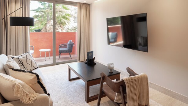A modern living room with a sofa, a dining table, and a TV mounted on the wall. - Laiva Artwalk by Tasman (San José del Cabo)