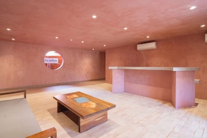 A spacious room with a wooden table, a reception desk, and a circular sign on the wall.