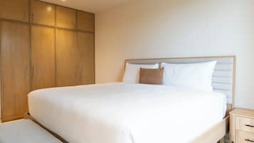A bedroom with a large bed, wooden wardrobe, and a bedside table.
