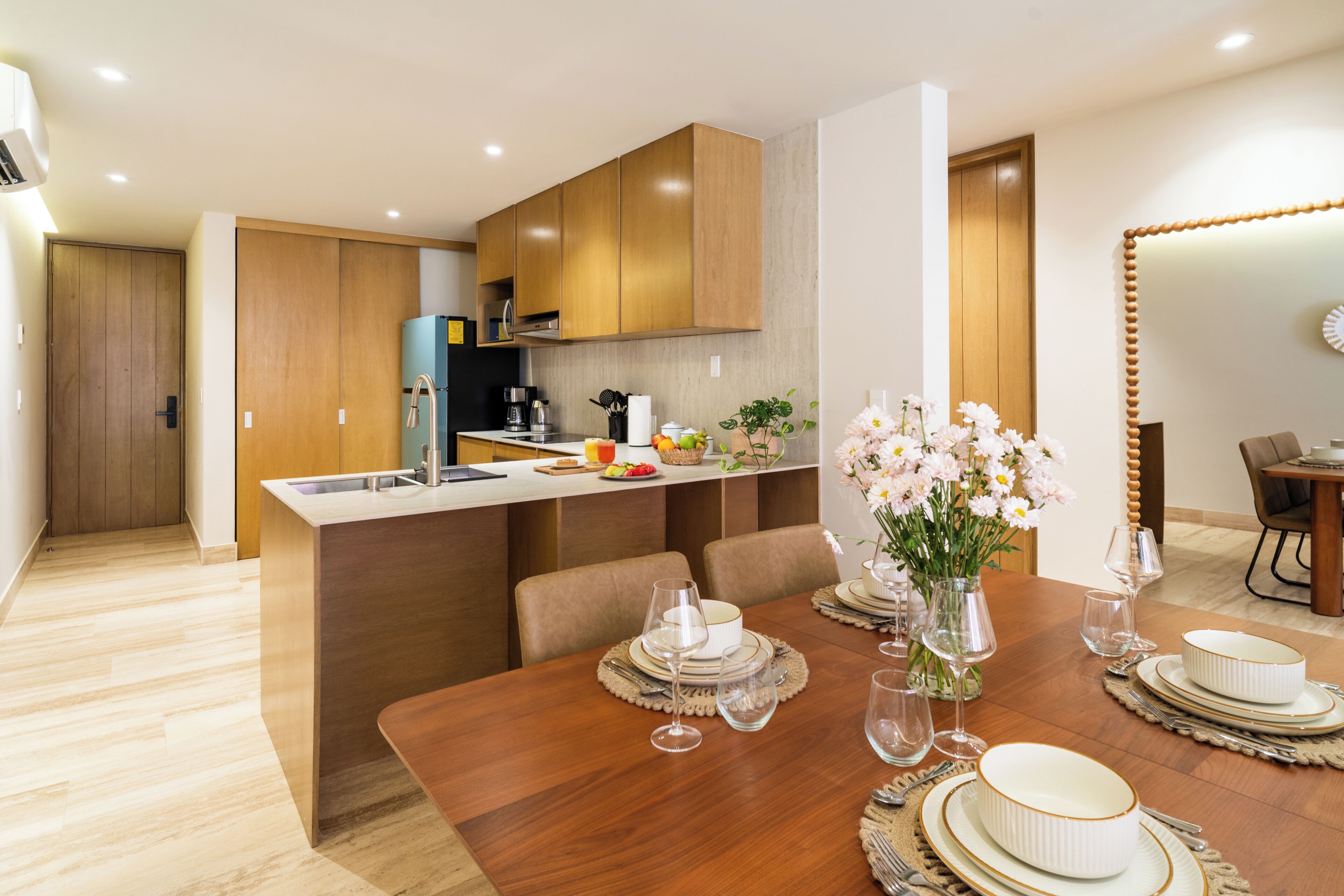 Eine moderne Küche mit Holzausstattung, einer integrierten Kochinsel und einem Essbereich mit einem Holztisch, gedeckt für eine Mahlzeit.