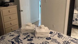 Une chambre à coucher comprenant un lit, une commode, un téléviseur et une porte donnant sur une autre pièce.