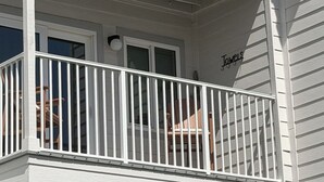 Un immeuble à plusieurs étages doté de balcons, une enseigne indiquant « Serviettes » et un panneau indiquant la direction de la plage.