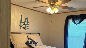 A bedroom with a bed, a ceiling fan, and a window with curtains.