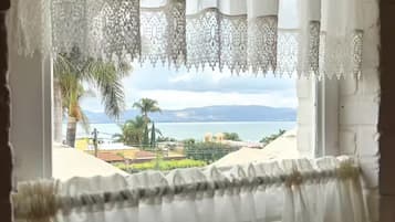 Una ventana con cortinas blancas y vista a un paisaje costero.