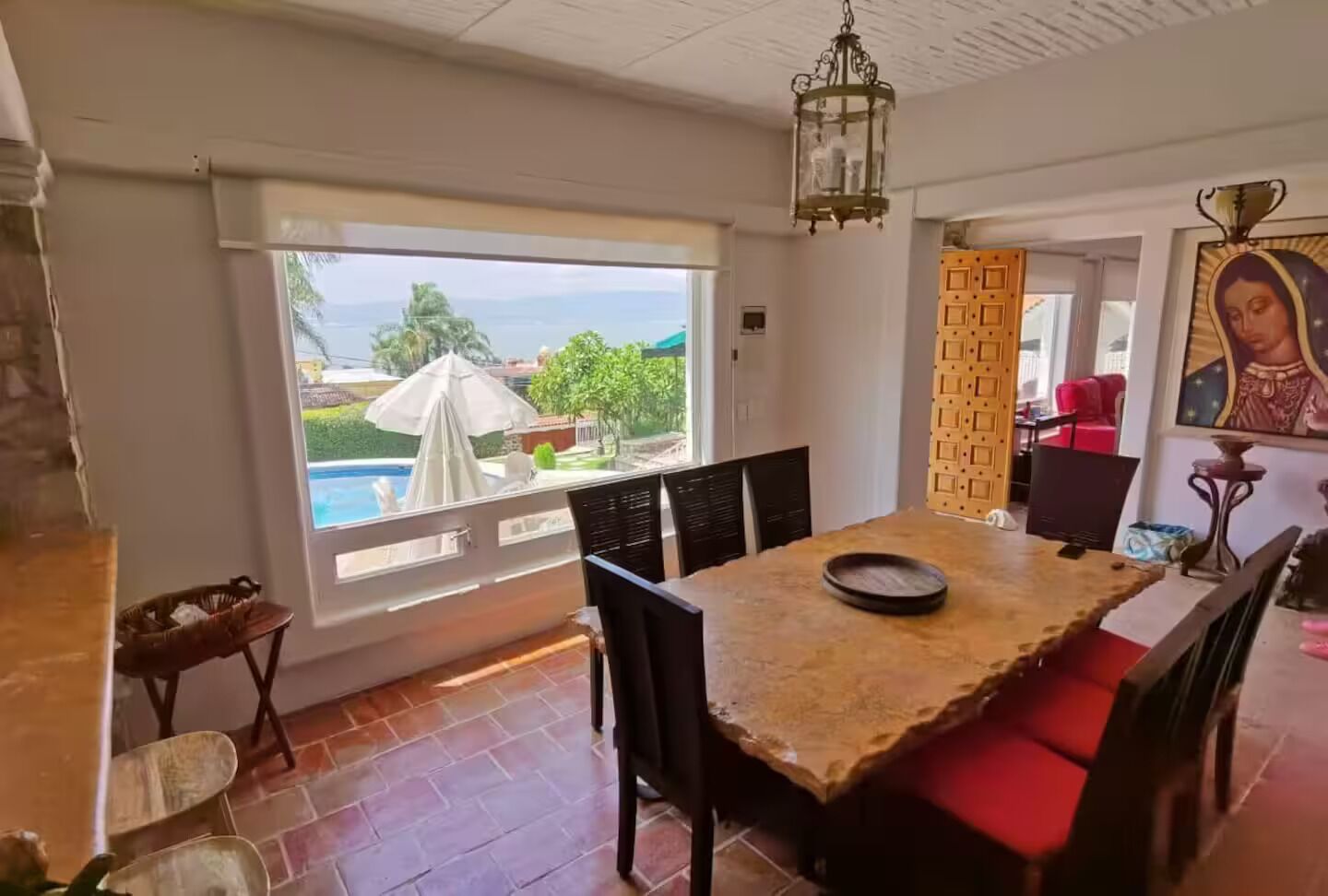 A dining area with a view of a swimming pool, a chandelier, and a religious painting.