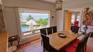 A dining area with a view of a swimming pool, a chandelier, and a religious painting.