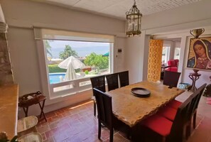 A dining area with a view of a swimming pool, a chandelier, and a religious painting.