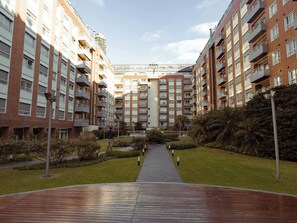 Un edificio residencial de varios pisos con balcones, un patio central y un camino que lleva a la entrada.