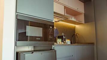 A modern kitchen with a built-in microwave, refrigerator, and a countertop with a coffee maker.