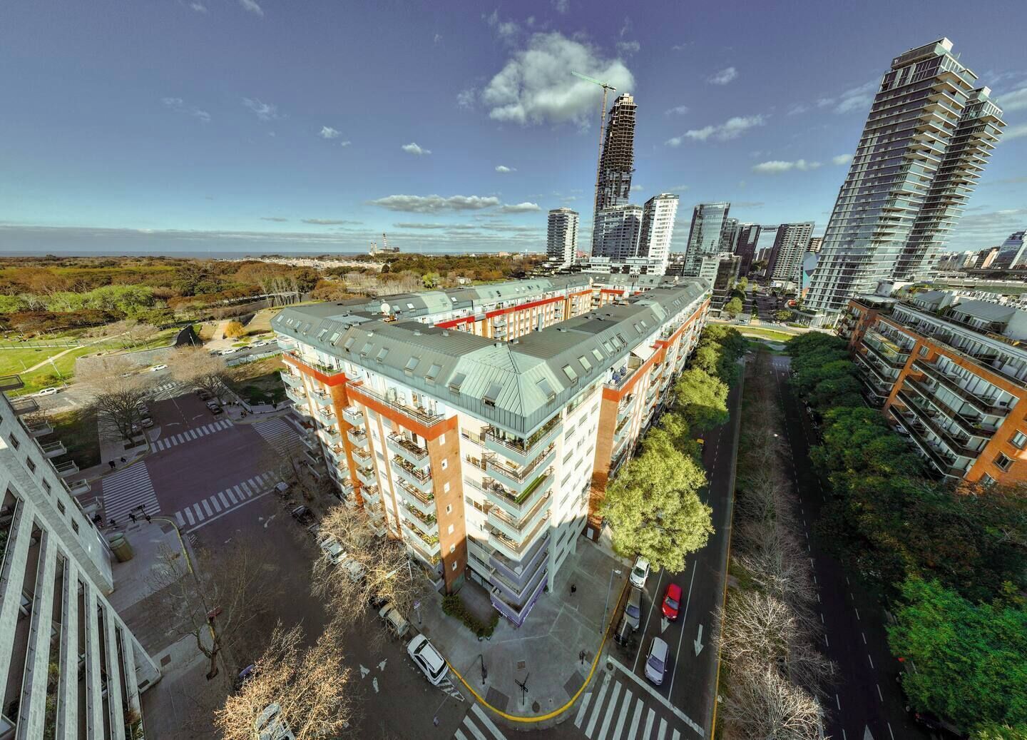 A multi-story building with a flat roof, surrounded by greenery and other high-rise buildings.