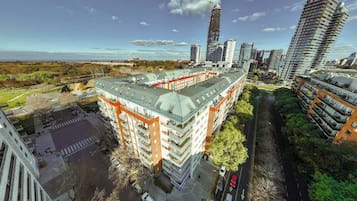 A multi-story building with a flat roof, surrounded by greenery and other high-rise buildings.