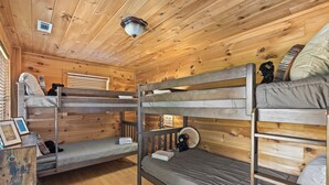 A bunk bed room with wooden walls and floors, a ceiling light, and a small table with a teddy bear. - Hoot Owl Lodge - Views, Bark Park, Arcade, Hot Tub (Blue Ridge)