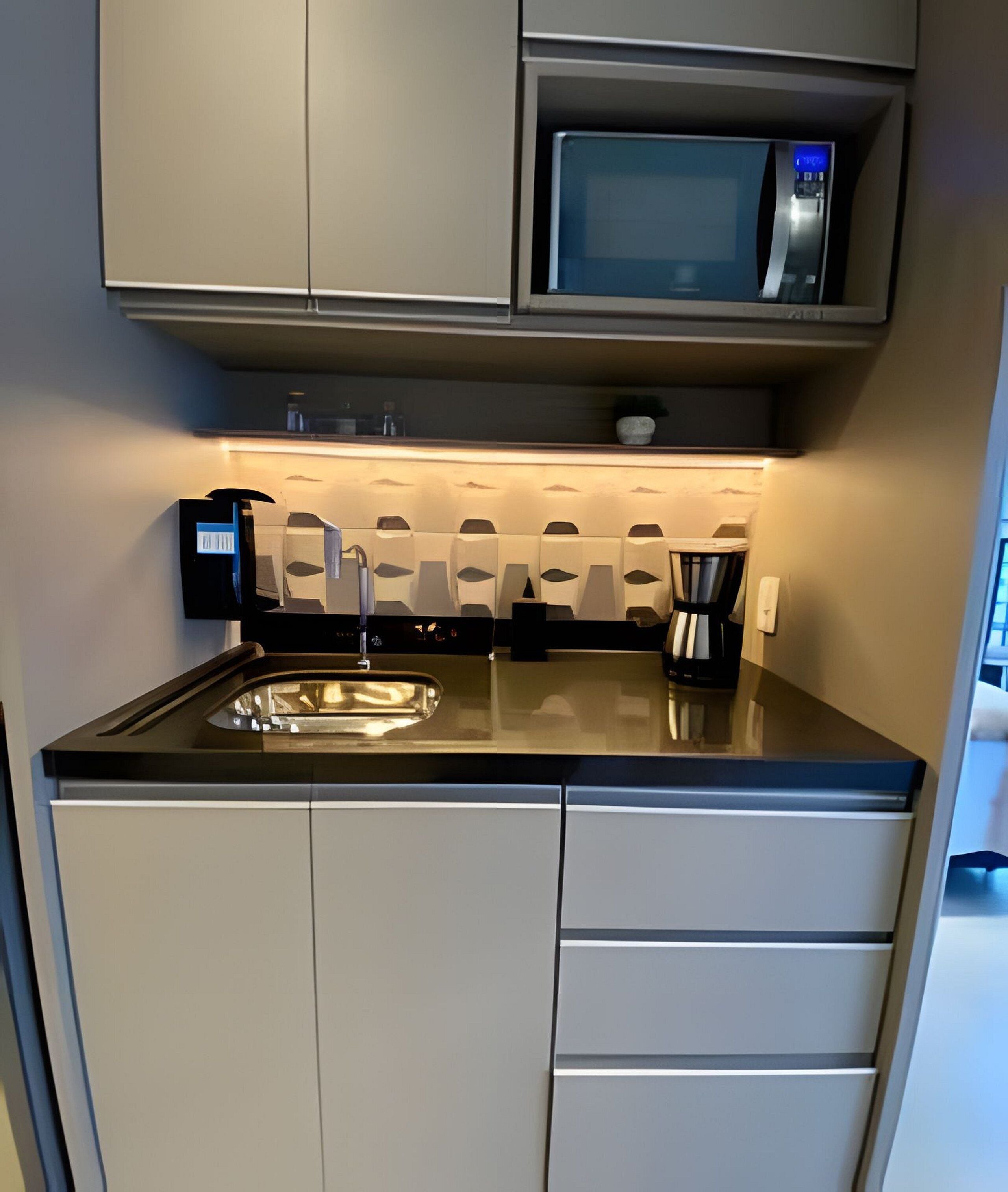 Une cuisine compacte équipée d’un four à micro-ondes, d’un évier et d’une machine à café.