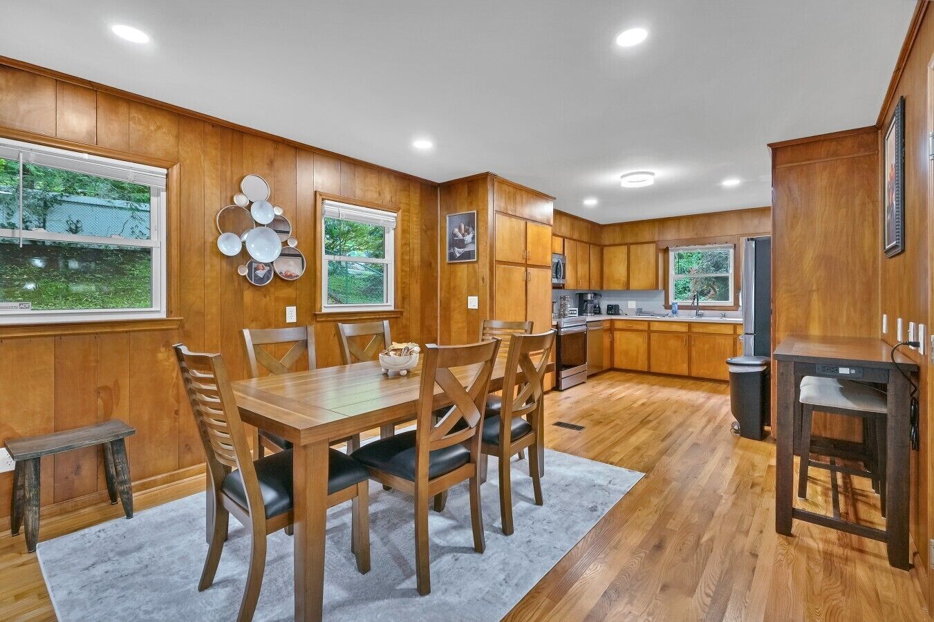 A wooden-paneled kitchen with a dining table and chairs, a refrigerator, and a microwave.