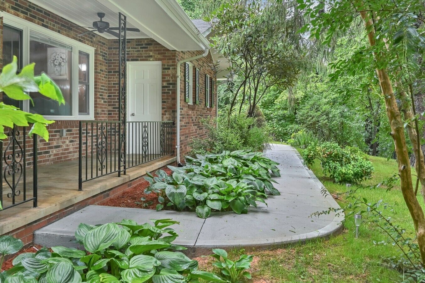 A brick house with a front porch, a white door, and a black railing.