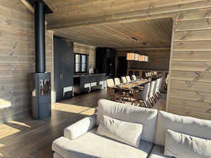 A modern interior with a sofa, dining table, and a black wood-burning stove.