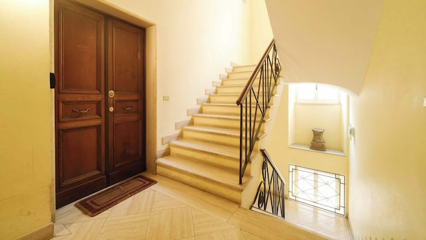 Eine Treppe mit einer Holztür und einem kleinen Regal.