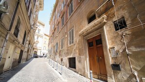 A narrow cobblestone street flanked by historic buildings with arched windows and a prominent wooden door.