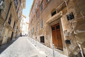 A narrow cobblestone street flanked by historic buildings with arched windows and a prominent wooden door.