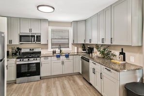 A modern kitchen with white cabinetry, stainless steel appliances, and a granite countertop.