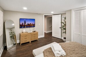 A bedroom with a bed, a dresser, a mirror, a painting of a cityscape, and a closet.