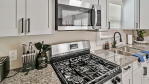 Une cuisine moderne dotée d’appareils électroménagers en acier inoxydable, de plans de travail en granit et de meubles blancs.