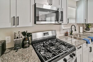 A modern kitchen with stainless steel appliances, granite countertops, and white cabinetry.