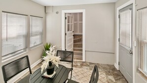 Une pièce comprenant une table à manger, des chaises, une plante en pot et un escalier menant à un niveau supérieur.
