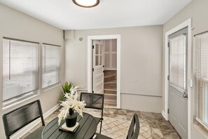 A room with a dining table, chairs, a potted plant, and a staircase leading to an upper level.