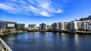 Ein Fluss mit Gebäuden an beiden Ufern, einem klaren Himmel und einer Brücke im Vordergrund.