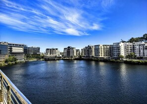 Ein Fluss mit Gebäuden an beiden Ufern, einem klaren Himmel und einer Brücke im Vordergrund.