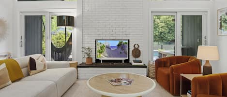 Un salon moderne avec une cheminée en briques blanches, un téléviseur, une table basse ronde et un canapé.